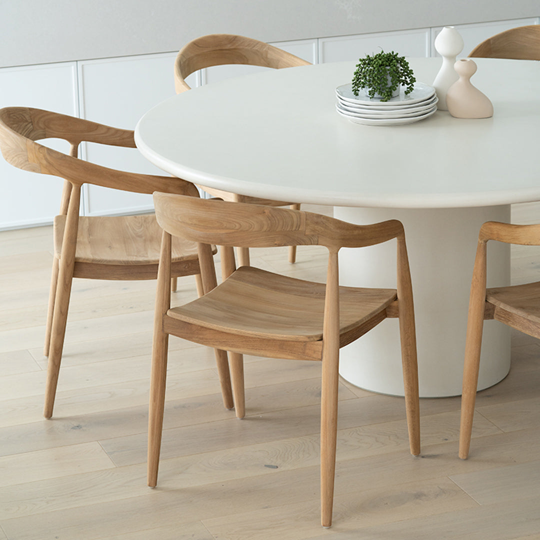 Angled lifestyle view of Rigby Armchair – Natural paired with round dining table.