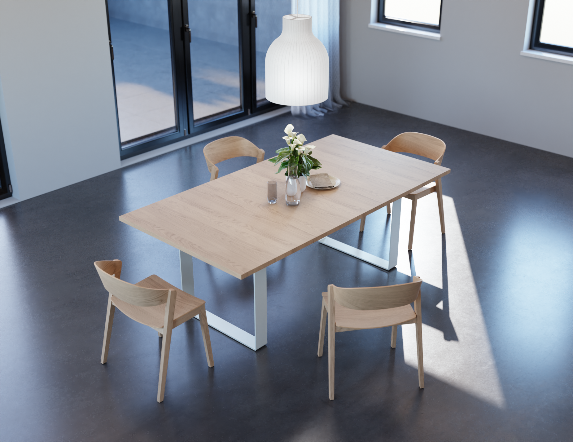 Angled aerial view of a modern dining room setting featuring four natural wooden chairs and wooden table top table all on a polished concrete floor.