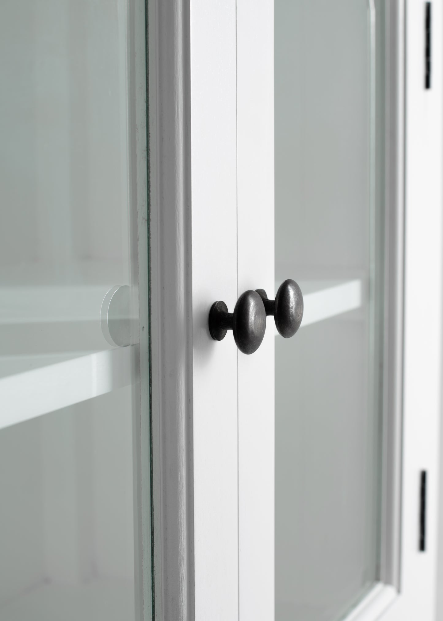 Close-up view of traditional 3 level white timber pantry door knobs and glass door.