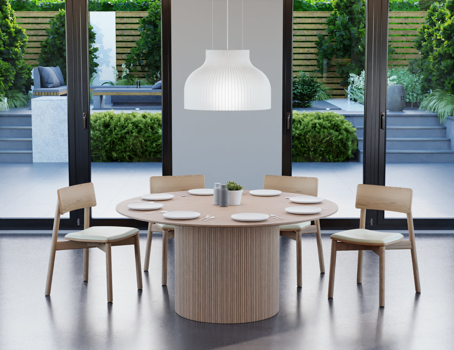 6 to 8 seater round dining table in natural American ash finish with 4 wooden chairs on a polished concrete floor next to large windows.