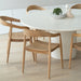 Angled lifestyle view of Rigby Armchair – Natural paired with round dining table.