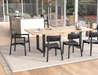Lifestyle dining room scene with Andi Armchair Black chairs סביב a rectangular wood dining table, showcasing modern interior with large glass windows, outdoor patio view, pendant lighting, and contemporary Scandinavian styling.