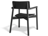 Rear three-quarter view of Andi Armchair Black modern wooden dining chair, featuring matte black finish, curved backrest, integrated armrests, sculpted seat, and solid wood frame isolated on a neutral background.