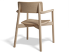 Rear three-quarter view of Andi Armchair Natural solid wood chair, emphasising curved back panel, angled legs, supportive frame, and natural oak grain texture on a white background.