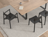 Top angled view of Andi Dining Chair Black around a wooden dining table on textured rug, highlighting arrangement and modern dining setup.