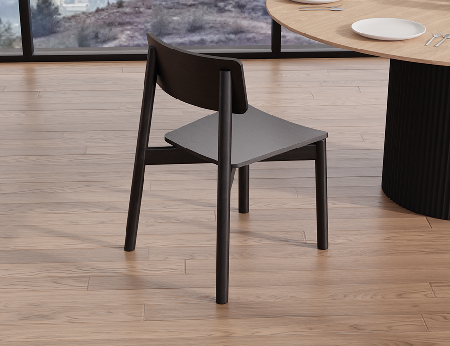 Rear angled view of Andi Dining Chair Black in a modern dining space with light wood flooring and round table, showcasing minimalist design and matte black finish.