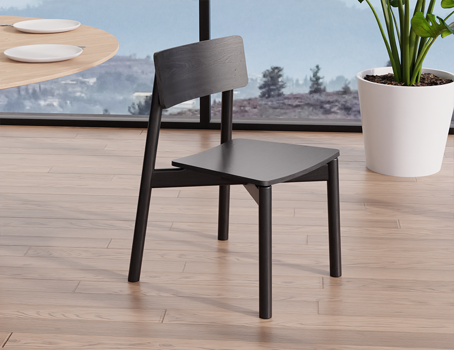Side perspective of Andi Dining Chair Black near a dining table and indoor plant, highlighting clean lines, solid wood construction, and contemporary Scandinavian style.