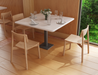 Modern cafe interior with square white table and glassware place settings, featuring Andi Dining Chair Natural in a light wood Scandinavian setting.