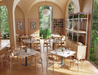 Spacious restaurant interior with arched windows, warm lighting, and multiple tables styled with Andi Dining Chair Natural.