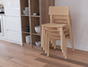 Stackable wooden chairs in kitchen interior beside open shelving, featuring Andi Dining Chair Natural functional design.