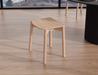 Front perspective view of Andi Low Stool Natural 45 cm Seat Height placed in modern interior with wooden flooring, highlighting compact size and organic form.