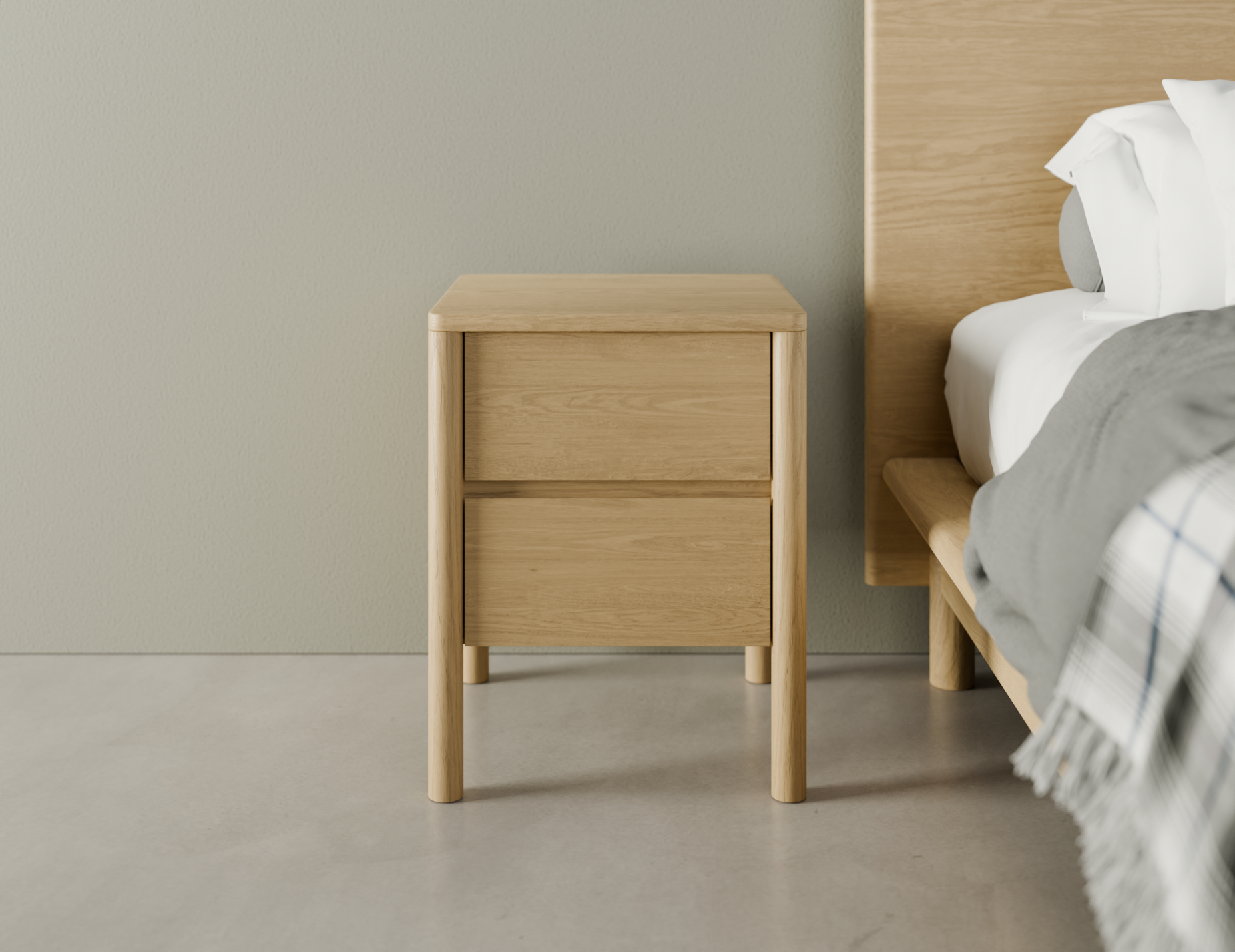 Simple natural wooden bedside table with two drawers beside a bed.