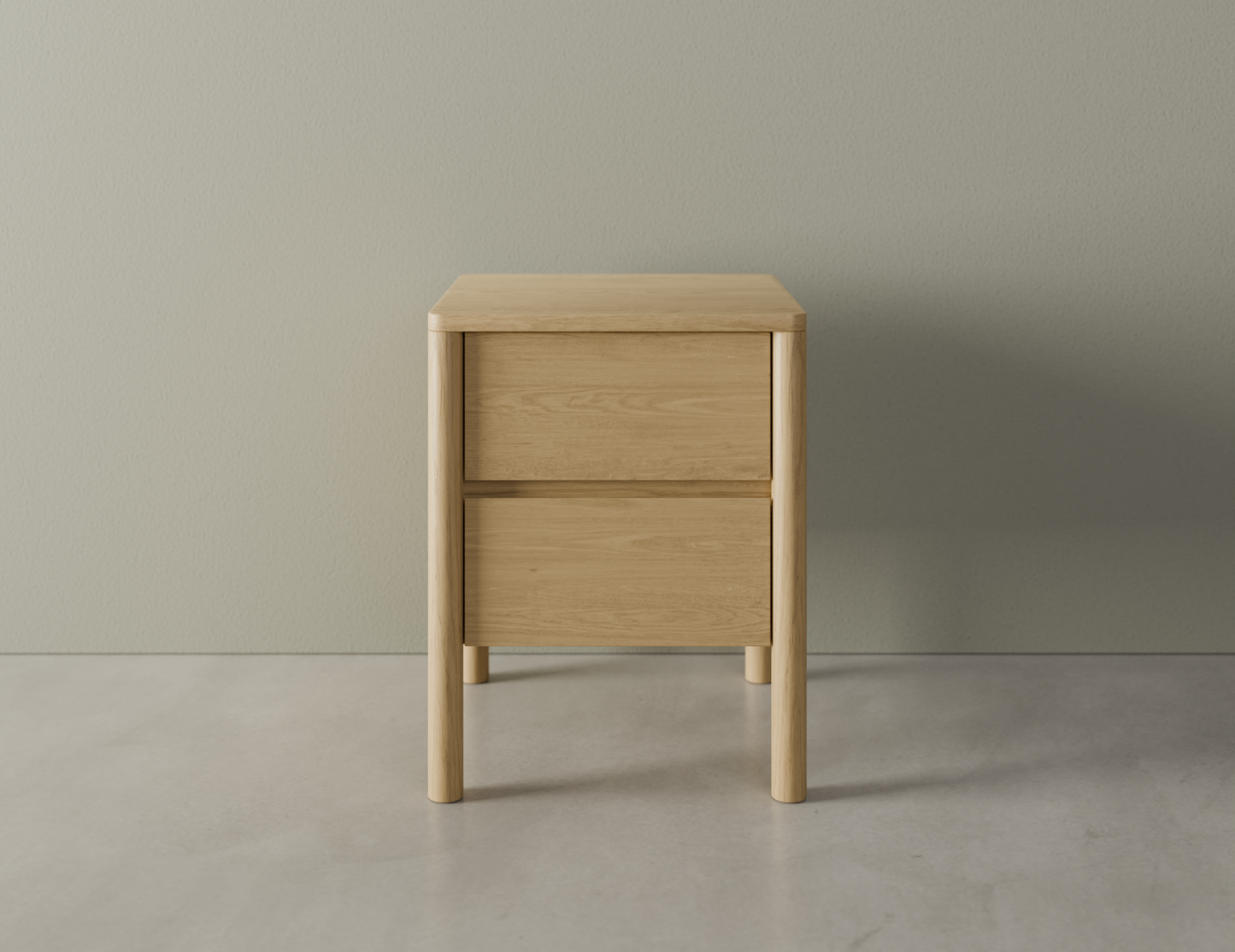 Front view of bedside table in natural wood finish with two drawers, rounded edges and legs on a polished concrete floor.
