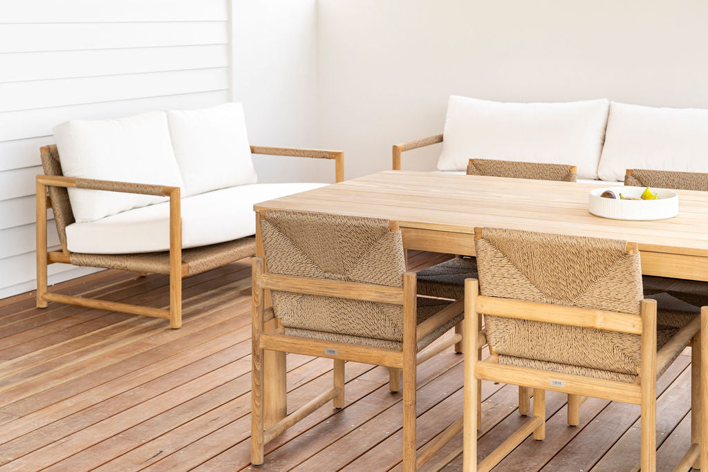 Esperance Outdoor Dining Chair set around large teak table with matching outdoor sofa and love seat, on wood deck.