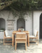 Esperance Outdoor Dining Chairs with white cushions and teak table on patio under tree canopy, styled Mediterranean setting.