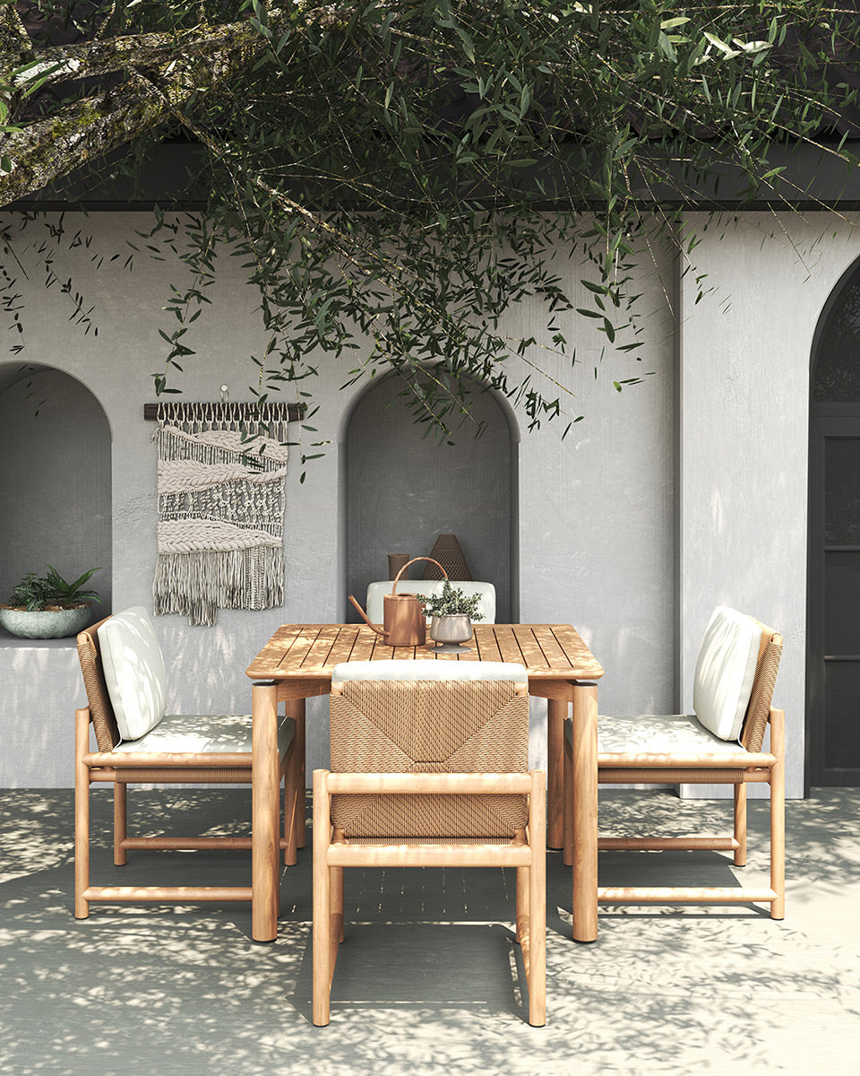 Esperance Outdoor Dining Chairs with white cushions and teak table on patio under tree canopy, styled Mediterranean setting.
