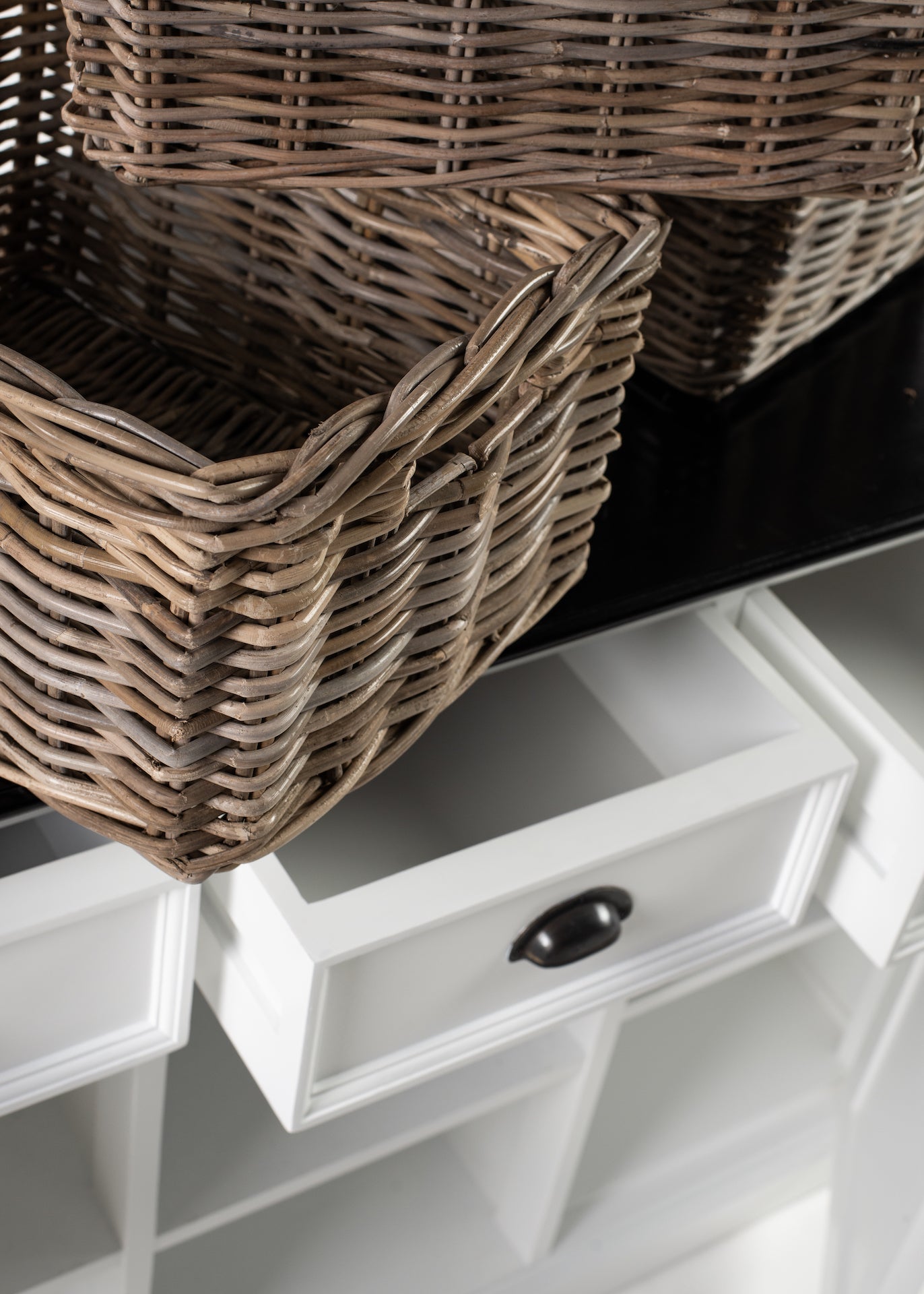 Close-up of rattan baskets stacked on and inside the Halifax Contrast Buffet with an open drawer below.