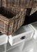 Close-up of rattan baskets stacked on and inside the Halifax Contrast Buffet with an open drawer below.