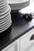 Close-up of the Halifax Contrast Buffet with Sliding Doors black timber top, styled with stacked plates and cutlery.