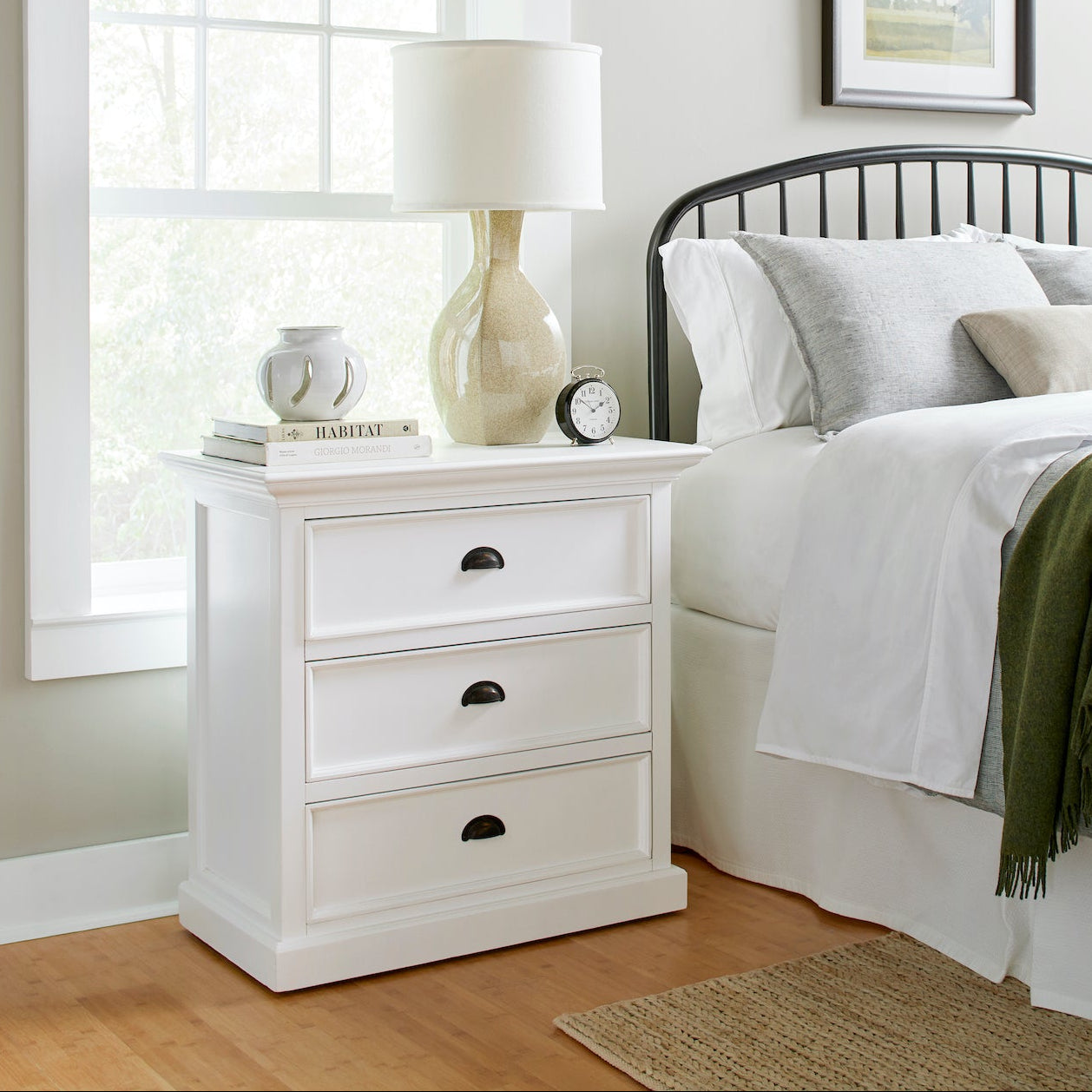 Halifax Grand Bedside Drawer Unit styled beside a bed with a lamp, books, alarm clock and soft neutral bedding.