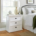 Halifax Grand Bedside Drawer Unit styled beside a bed with a lamp, books, alarm clock and soft neutral bedding.