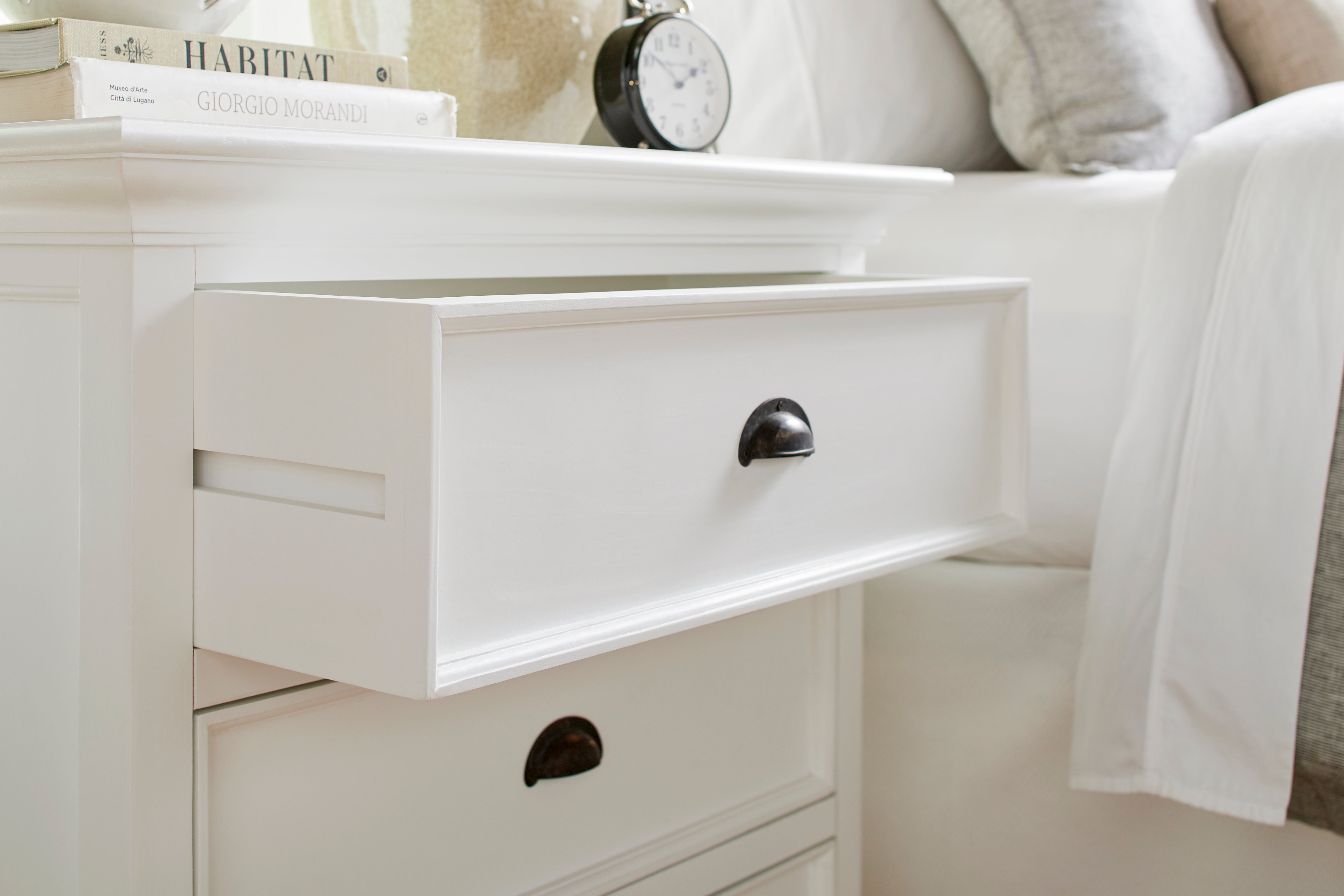 Close-up of an open drawer on the Halifax Grand Bedside Drawer Unit beside a bed, showing the black cup handle and white drawer front.