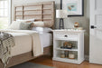 Close-up of the Halifax Grand Bedside Table styled with an open book, glasses, lamp and decorative objects.