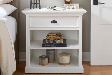 Halifax Grand Bedside Table styled beside a bed with books, lamp, decorative boxes and open shelves.