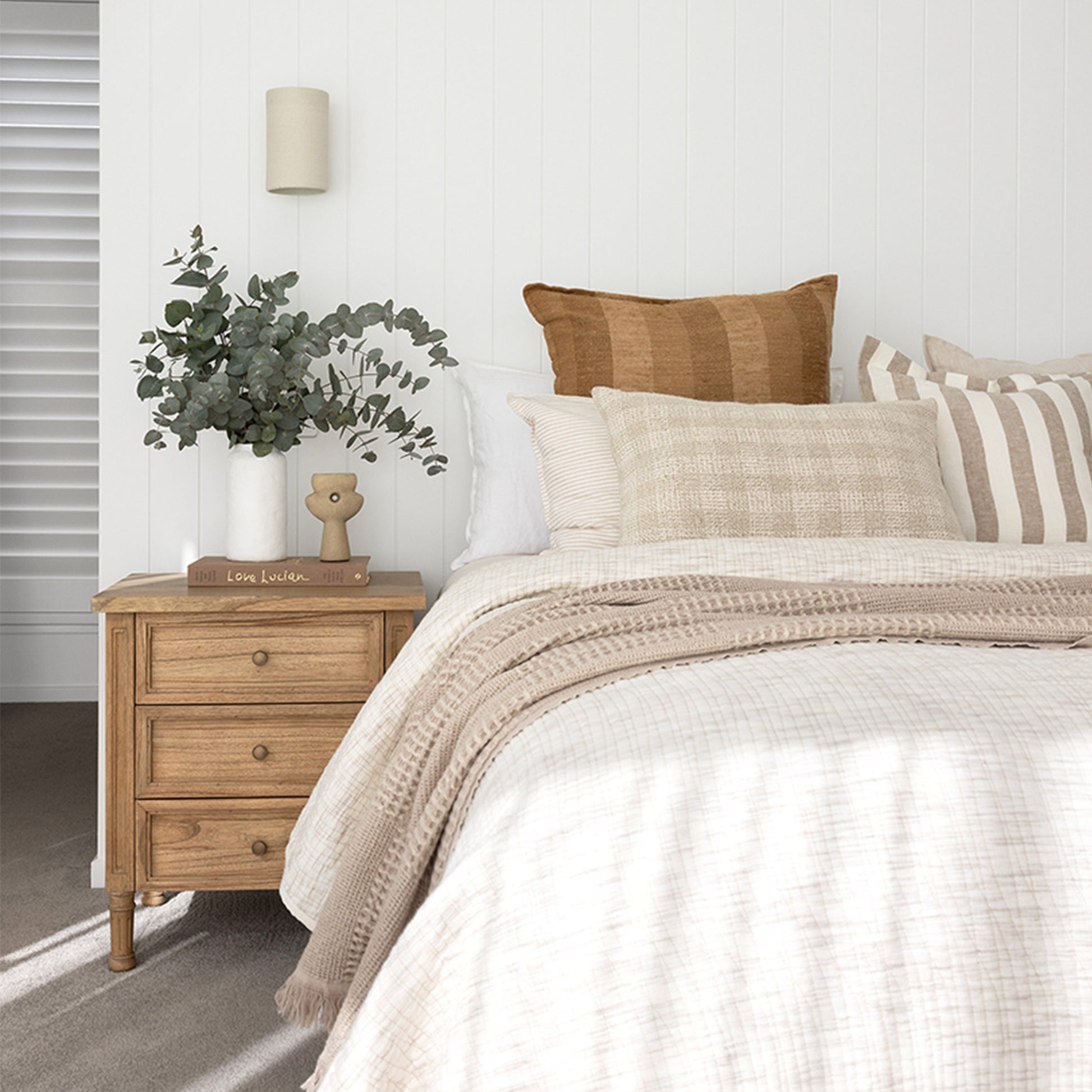 Close-up lifestyle view of Hamilton 3 drawer bedside table – Natural with decor styling beside bed.