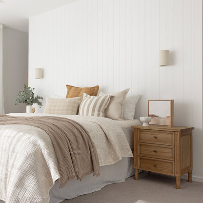 Lifestyle bedroom view of Hamilton 3 drawer bedside table – Natural styled beside bed with cushions and throw.