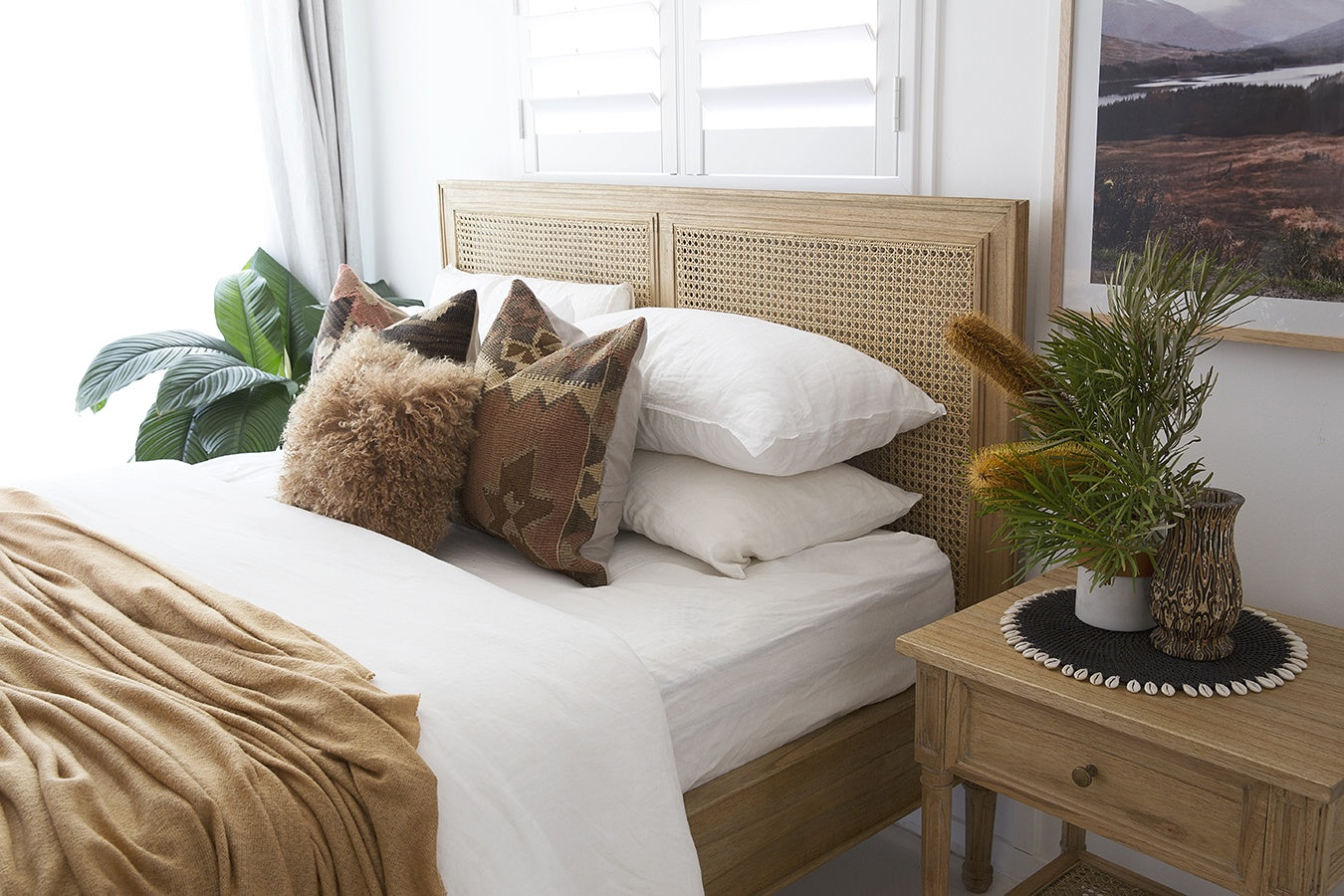 Angled view of Hamilton Cane Super King Bed in Weathered Oak with woven rattan headboard, white linen bedding and timber bedside table