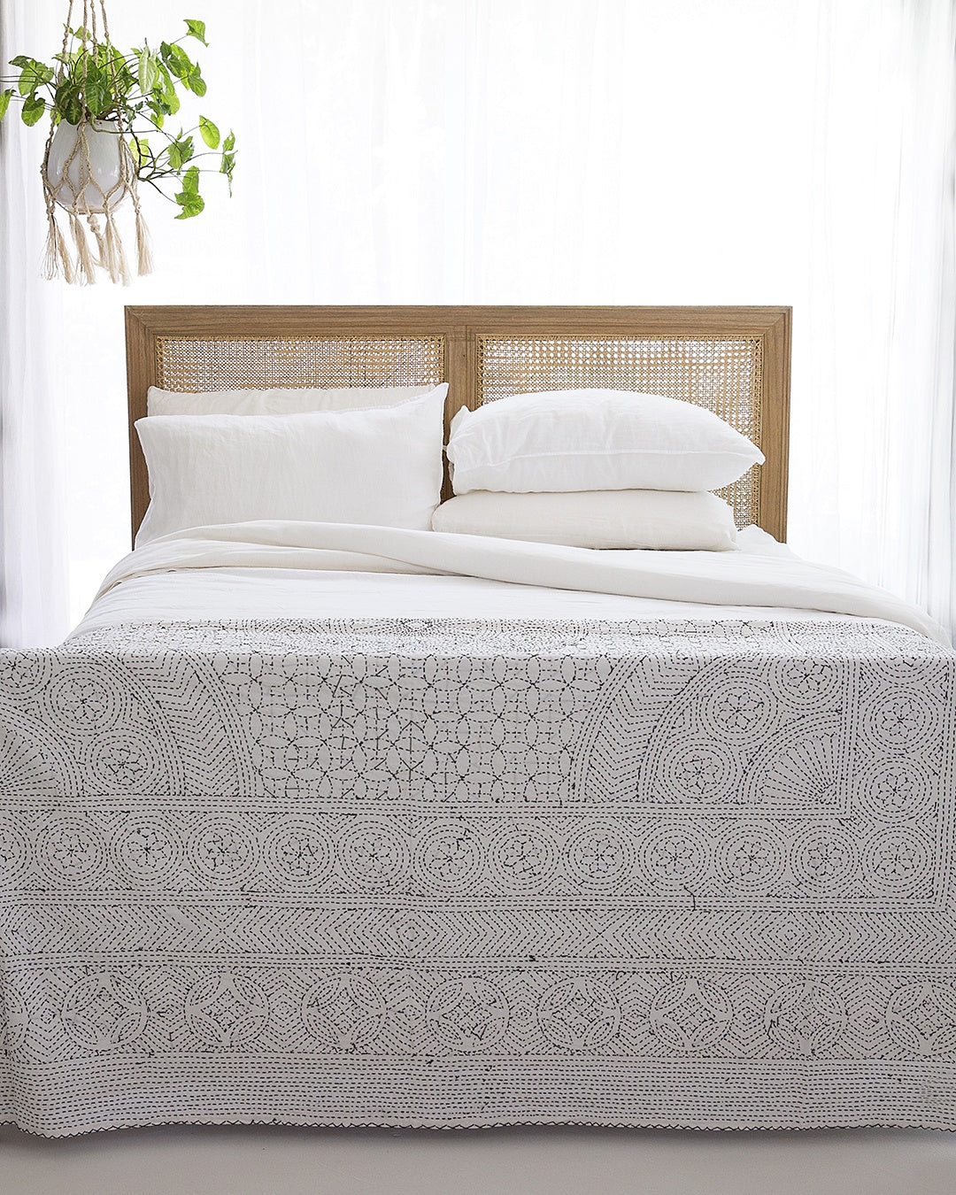Front view of Hamilton Cane Super King Bed with woven rattan headboard styled with white bedding and patterned throw blanket