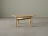 Nordica round wooden coffee table in natural oak finish on a polished concrete floor.