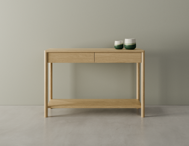 Nordica wooden console table in natural oak finish with 2 drawers displaying 2 ceramic ornaments on a polished concrete floor.