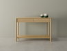 Nordica wooden console table in natural oak finish with 2 drawers displaying 2 ceramic ornaments on a polished concrete floor.