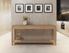 Nordica wooden console table in natural oak finish with 3 drawers against a concrete wall with 4 pictures hanging above in a modern house.