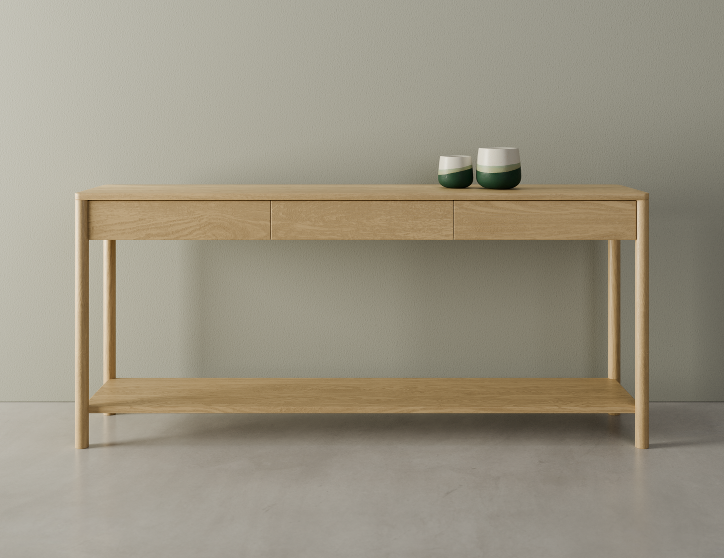 Front view of Nordica wooden console table in natural oak finish with 3 drawers on a polished concrete floor displaying 2 ceramic ornaments.