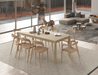 Nordica wooden dining table and chairs in natural oak finish on a natural rug in a light filled open plan room.