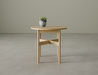 Round side table in natural wood finish with a potted plant on top on a polished concrete floor.