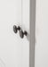 Close-up view of antique brass hardware on white wooden buffet doors.