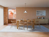 Wide room view of Pier Dining Table - Solid Oak - 160 cm x 90 cm positioned on a large rug beneath a pendant light in a contemporary dining interior.