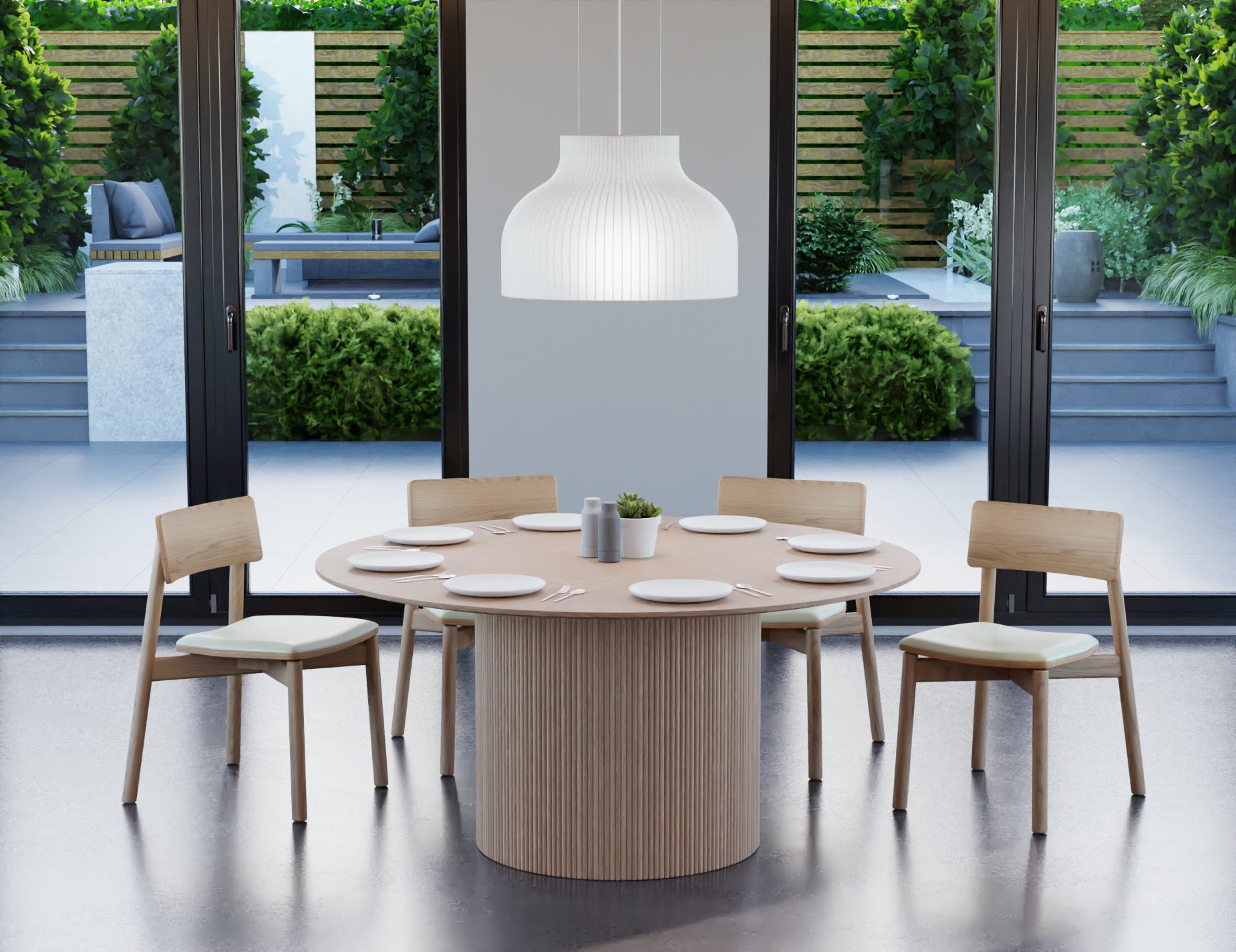 6 to 8 seater round dining table in natural American ash finish with 4 wooden chairs on a polished concrete floor next to large windows.