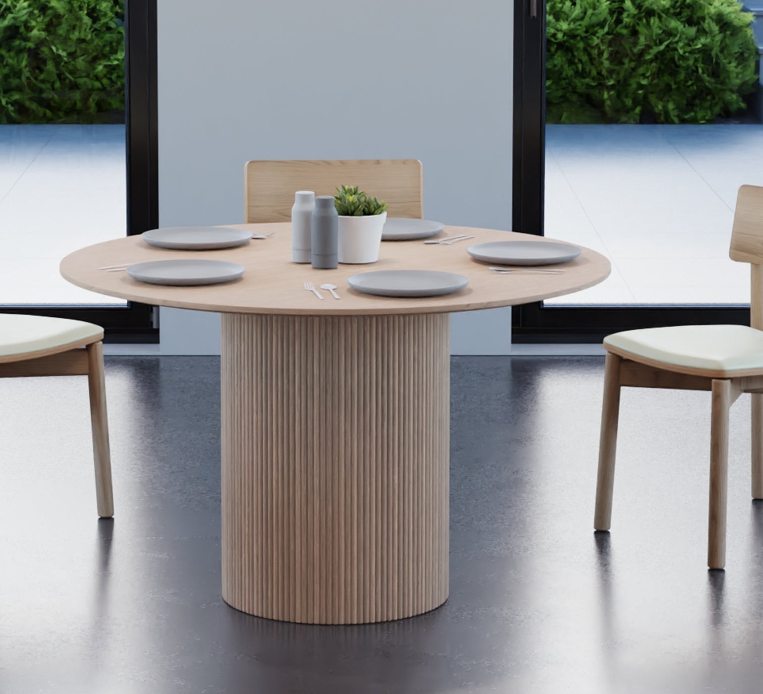 4 to 5 seater round dining table in natural American ash finish with 3 wooden chairs on a polished concrete floor.