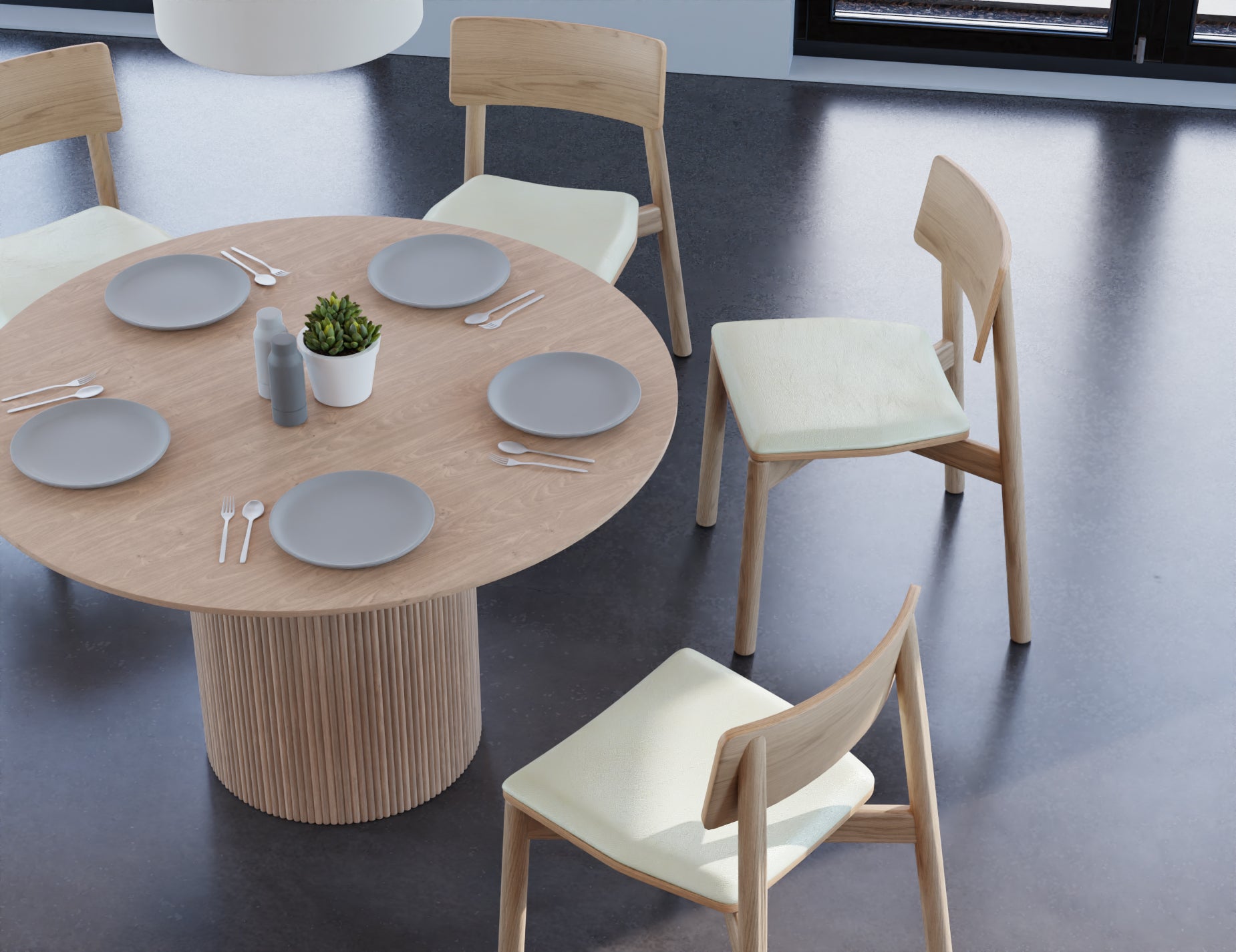 Slight aerial view of 4 to 5 seater round dining table in natural American ash finish with 4 wooden chairs on a polished concrete floor.