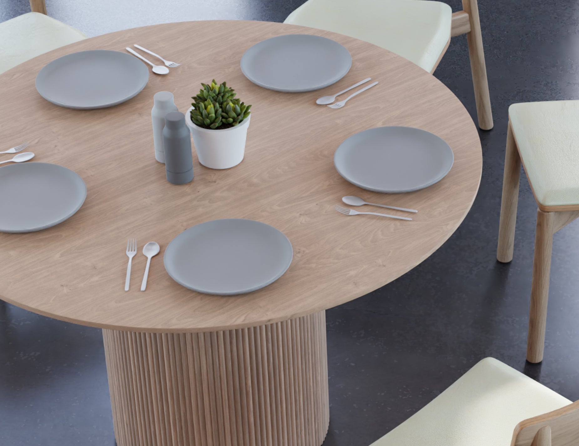 Close up aerial view of 4 to 5 seater round dining table in natural American ash finish displaying plates and cutlery with 4 wooden chairs on a polished concrete floor.