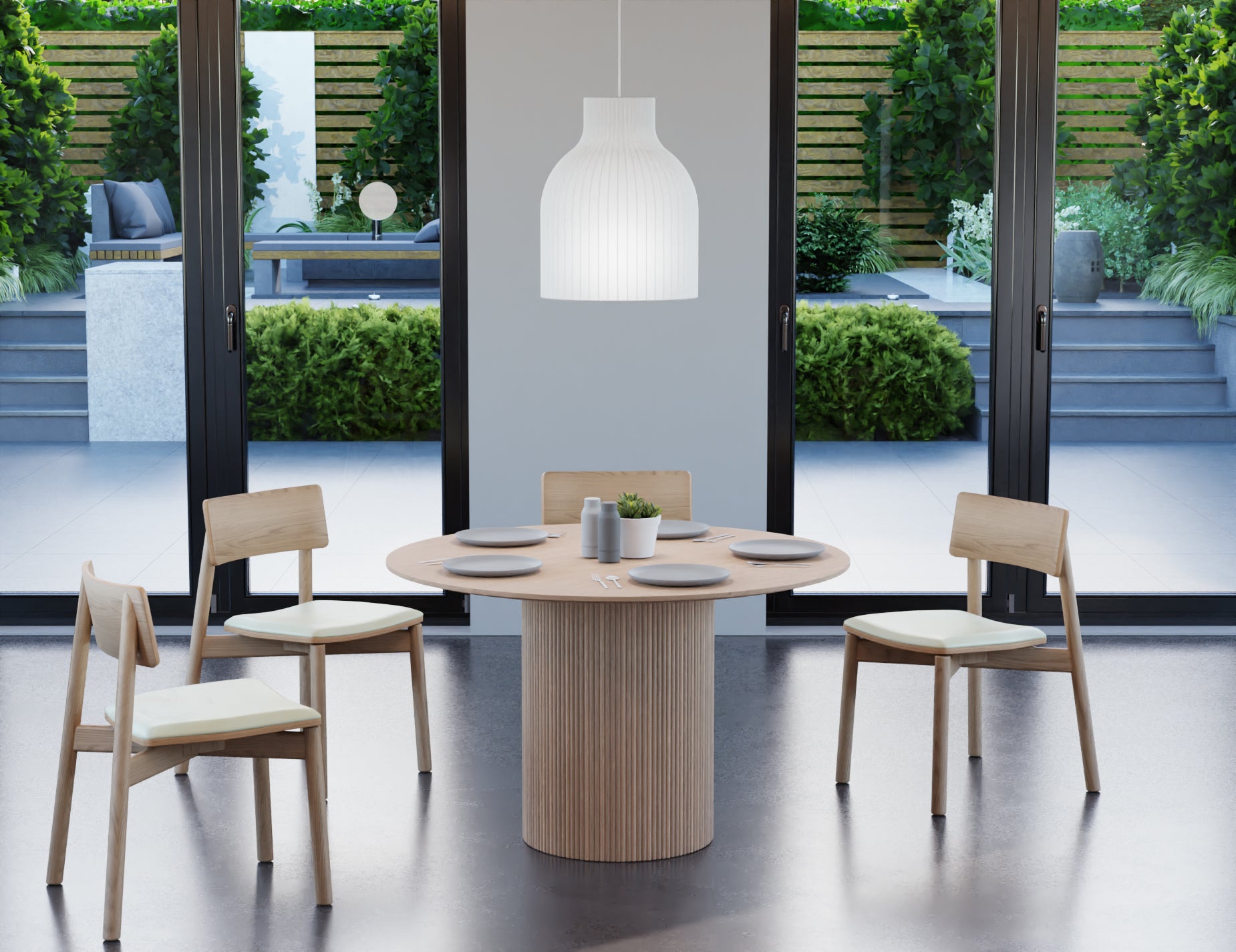 4 to 5 seater round dining table in natural American ash finish with 4 wooden chairs on a polished concrete floor next to large windows looking outside.