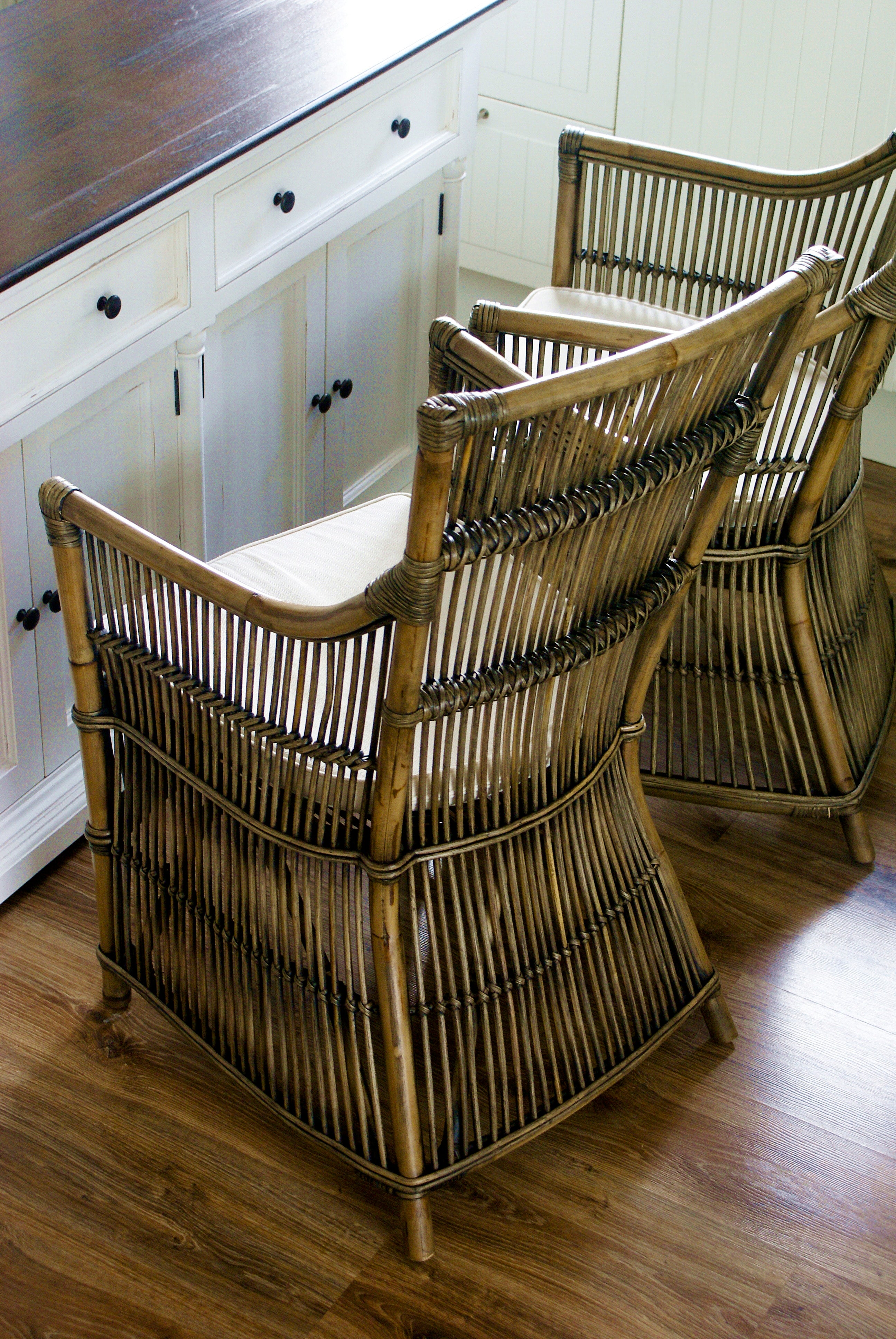 Two rattan dining chairs with white seat cushions shown from behind, styled beside the Provence Accent Classic Buffet in a coastal kitchen setting.