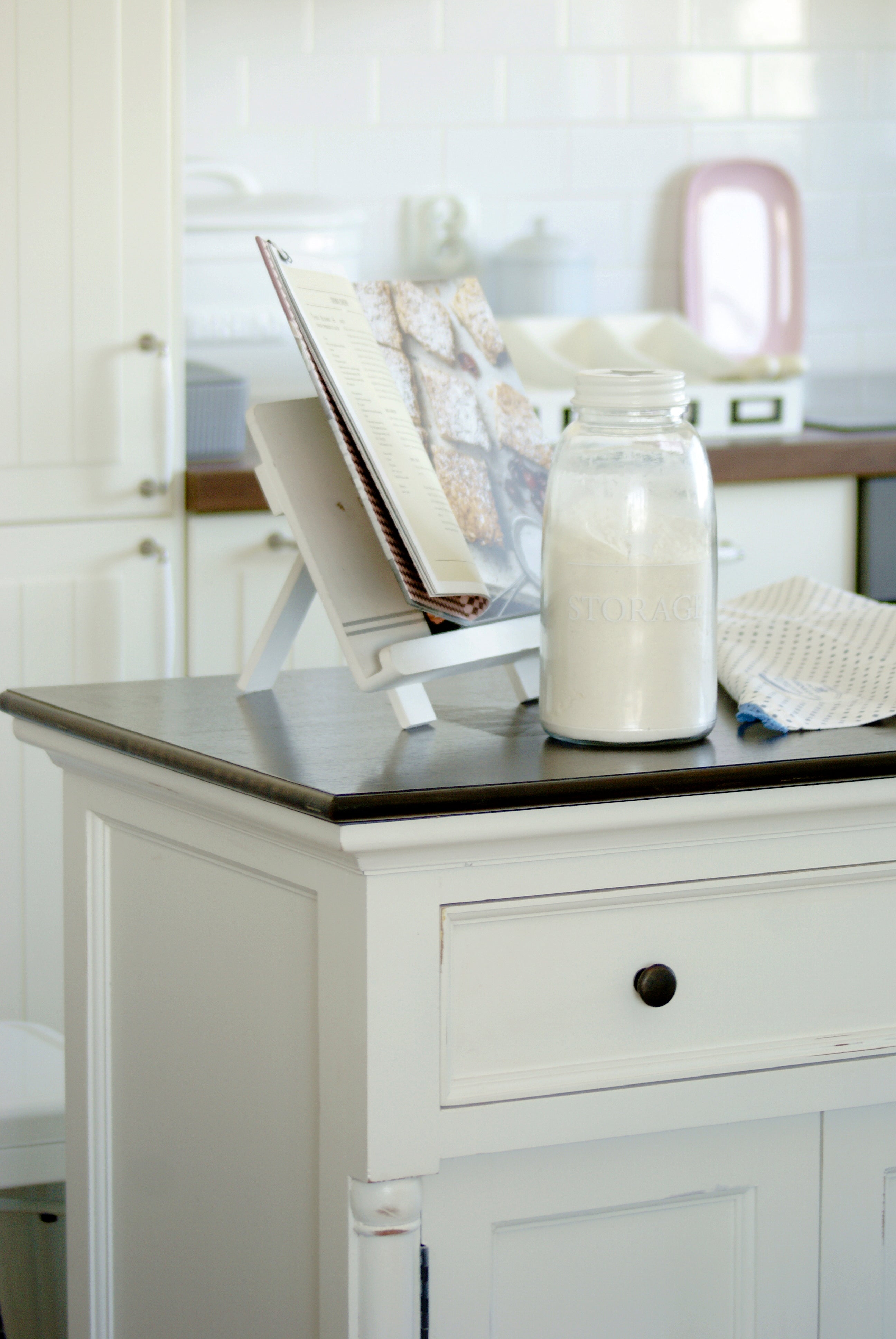Close-up of the Provence Accent Classic Buffet styled with a recipe book, storage jar and dark timber top in a light kitchen.