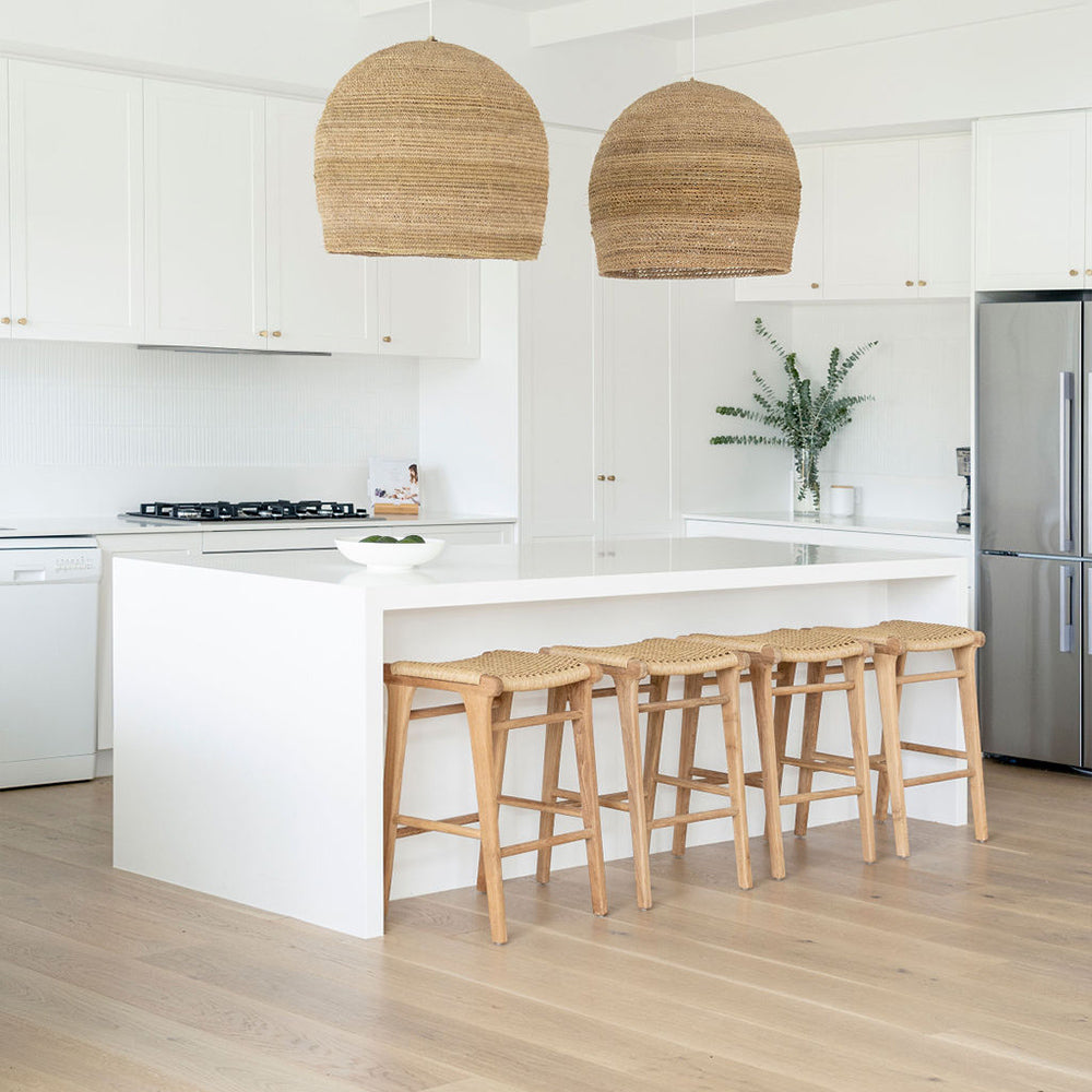 Bright modern kitchen with four Zen Backless Bar Stools – Sand – Open Weave and oversized woven pendant lights.