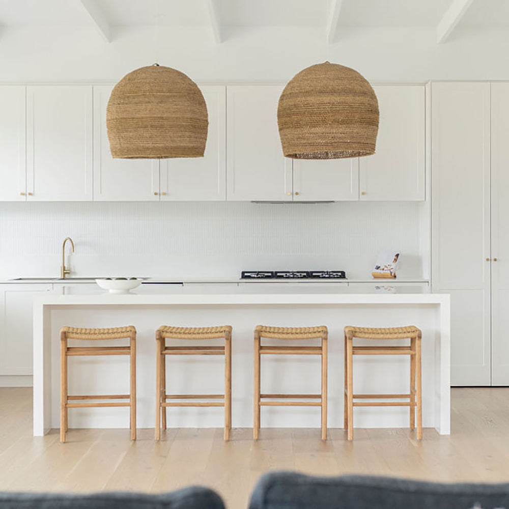 Clean white kitchen space with four Zen Backless Bar Stools – Sand – Open Weave positioned beneath a breakfast counter.